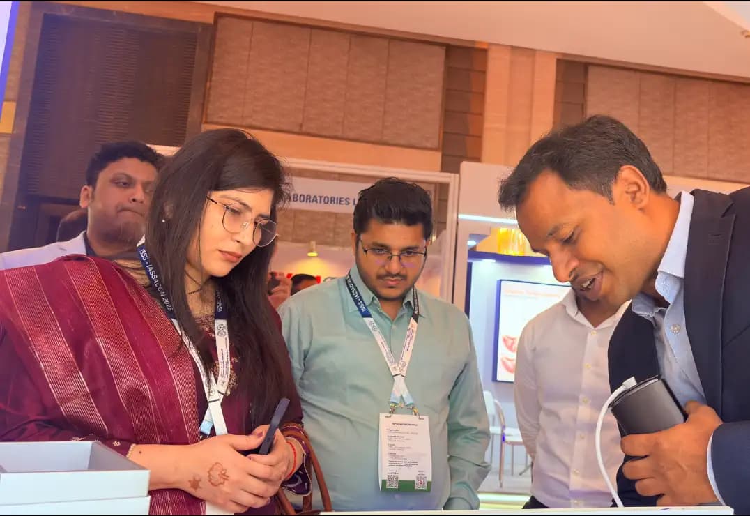 Attendees examining a handheld device at the Taevas Life Sciences stall